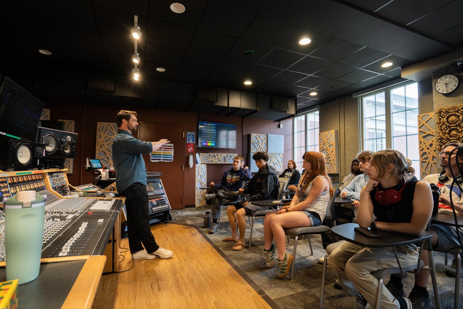 Participants watch a demonstration beside a mixing console in a studio on the University of Rochester’s River Campus.